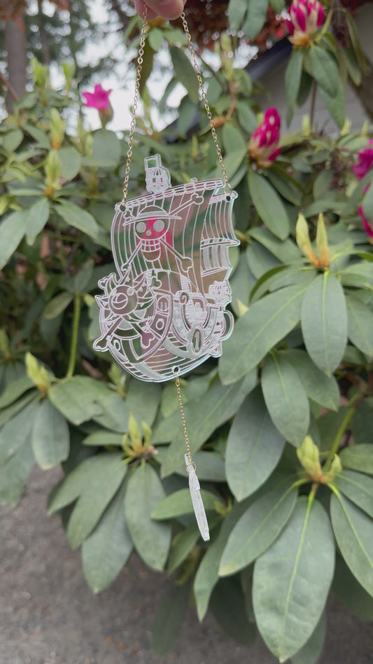 Iridescent pink acrylic pirate-themed suncatcher hanging outside and casting vibrant reflections—anime-inspired nautical design